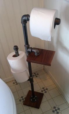 a toilet paper holder with two rolls of toilet paper on it and a wooden stand in the corner