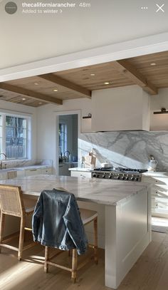 a kitchen with white cabinets and marble counter tops, an island bench is in the foreground