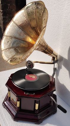 an old fashioned record player sitting on top of a wooden stand with its horn up