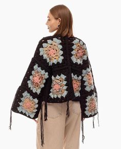 a woman wearing a black crochet jacket with flowers on it