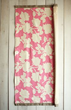 a pink and white flowered towel hanging on a wall