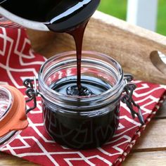 a person pouring chocolate into a jar on top of a red and white table cloth