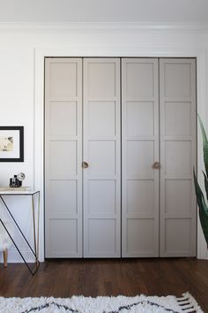 an empty room with white closet doors and wood flooring, along with a rug on the floor