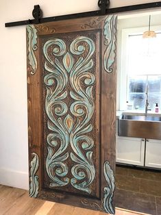 an ornate wooden door with blue and brown designs on the front, hanging in a kitchen