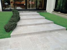 a set of steps leading up to a patio with grass and potted plants in the background