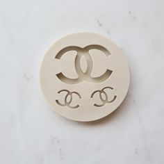 a white ceramic brooch with two eyes and the word chanel on it's face