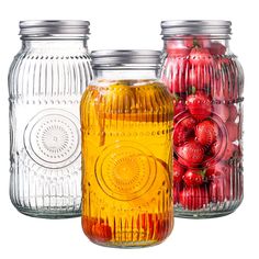 three glass jars with red and yellow ornaments in each jar, one filled with cherries