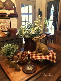 a wooden table topped with potted plants next to a candle and bunny figurine