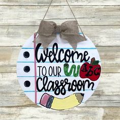 a welcome sign hanging on the side of a wooden wall with a ribbon around it