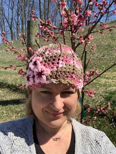 a woman wearing a crocheted hat with pink flowers