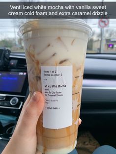 a person holding up a cup of iced coffee in their hand with information on it