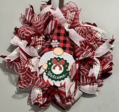 a red and white christmas wreath with a welcome sign on the front door hanger