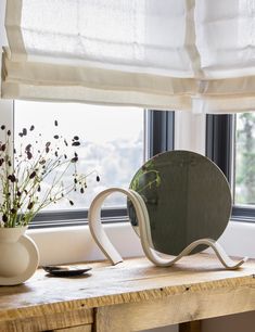 a mirror sitting on top of a wooden table next to a window