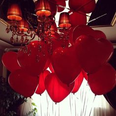 a bunch of red heart shaped balloons hanging from the ceiling