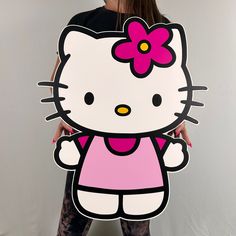 a woman holding a cardboard cutout of hello kitty with a flower in her hair