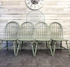 three green chairs sitting next to each other in front of a wall with a clock on it