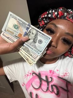 a woman holding money in her hands and wearing a bandana on top of her head