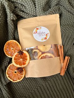 an open bag of dried oranges next to cinnamon sticks and star anise on a green sweater