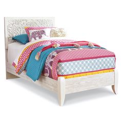 a white bed topped with lots of pillows and colorful blankets on it's headboard