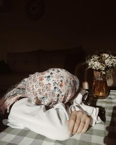 a woman laying on top of a bed next to a vase with flowers in it