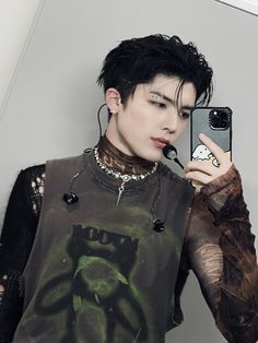 a young man with black hair is taking a selfie in front of a mirror