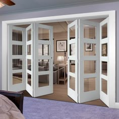 an open door leading into a bedroom with purple carpet and white furniture in the background