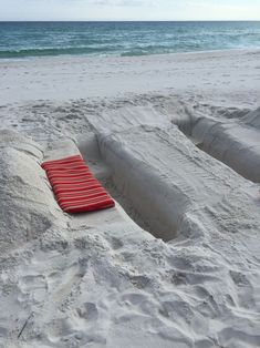 a red blanket laying on top of a sandy beach