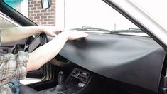 a man sitting in the driver's seat of a truck with his hand on the steering wheel