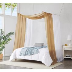 a bedroom with a white bed and orange drapes hanging from the ceiling over it