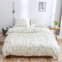 a white bed with yellow flowers on it in a room next to a wooden floor