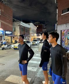 three young men standing on the side of a street