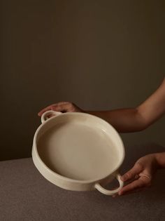 a person holding a white bowl on top of a table