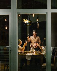 two men and a woman sitting at a table with wine glasses in front of them