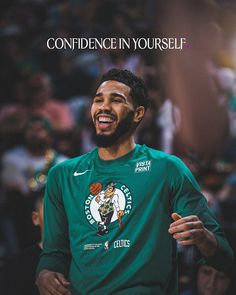 a man in green shirt standing on top of a basketball court with his hands out