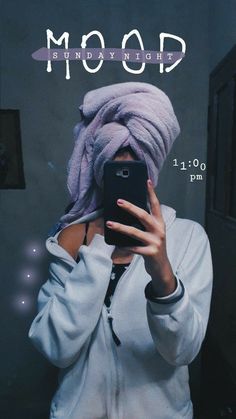 a woman taking a selfie in front of a mirror wearing a purple turban