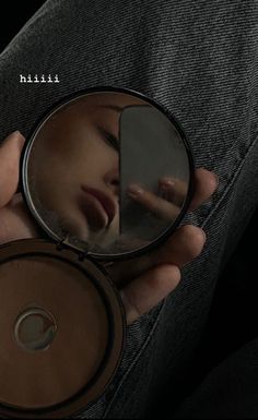 a person holding a compact mirror with their face reflected in it and the reflection of them