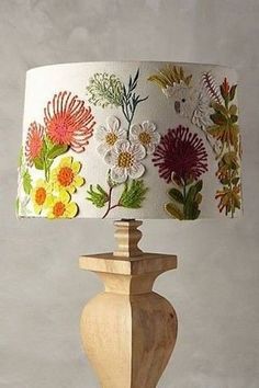 a lamp that is on top of a wooden base and has flowers painted on it