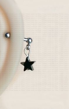 a black and white star charm hanging from a silver hook on a chain with a bead around it