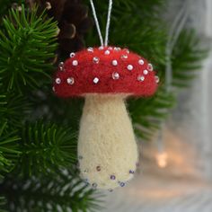 a red and white mushroom ornament hanging from a christmas tree