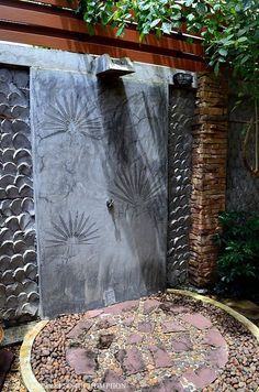 an outdoor shower in the middle of a garden with rocks around it and plants on either side