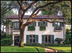 a white house with green shutters and trees