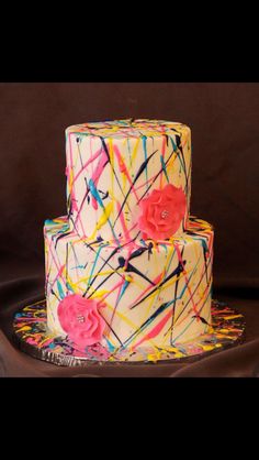 a three tiered cake with colorful icing and flowers