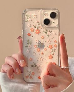 a woman is holding up her phone case with flowers on it and pointing to the side