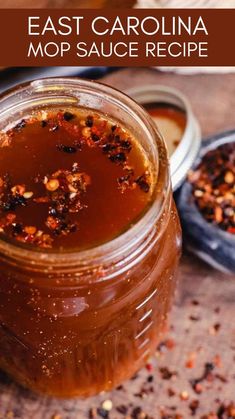 a jar filled with liquid sitting on top of a wooden table next to a spoon