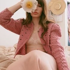 a woman sitting on top of a bed holding a flower