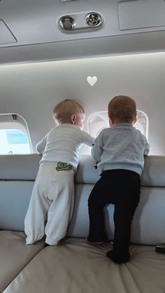 two toddlers playing on an airplane bed