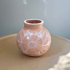 a pink vase sitting on top of a wooden table