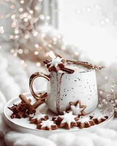 a cup and saucer on a white plate with some cinnamon stars in the middle