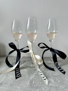 three wine glasses with ribbons tied around them