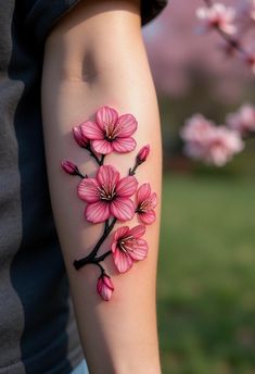 a person with a tattoo on their arm has pink flowers in the shape of a branch